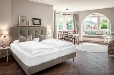 a bedroom with a large white bed and a living room at Villa Gloria in Soprabolzano