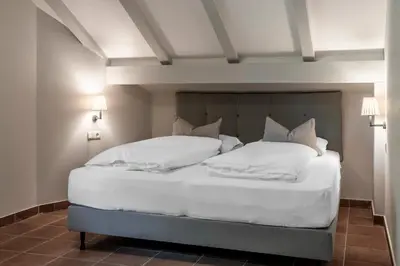 a bedroom with a bed with white sheets and pillows at Villa Gloria in Soprabolzano