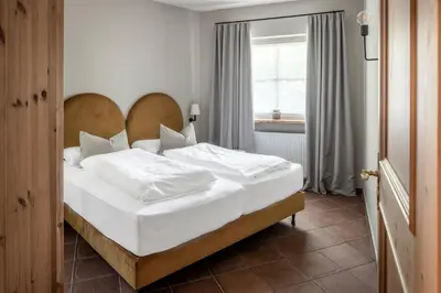 a bedroom with a bed with white sheets and a window at Villa Gloria in Soprabolzano