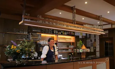 a woman standing behind a counter in a bar at Gasthof Schluff in Soprabolzano