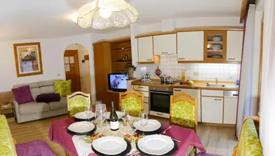 a kitchen and living room with a table and chairs at Villa Artic Apartments in Campitello di Fassa