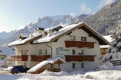 a large building with snow on the roof at Villa Artic Apartments in Campitello di Fassa