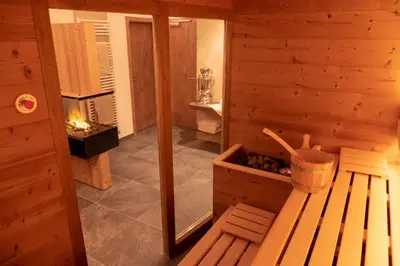 a room with a sauna with a bench and a fireplace at Villa Artic Apartments in Campitello di Fassa