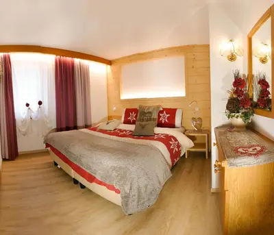 a bedroom with a large bed and a window at Villa Artic Apartments in Campitello di Fassa