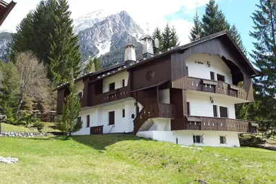 a building on a hill with a mountain in the background at Mansarda a San Vito di Cadore in San Vito di Cadore