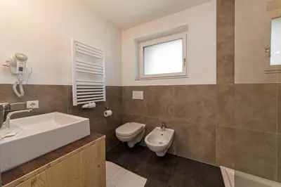 a bathroom with a sink toilet and a window at Appartement Wiere in Molini di Tures