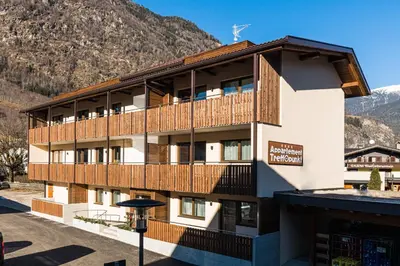 a building with wooden balconies and mountains in the background at Appartement Wiere in Molini di Tures