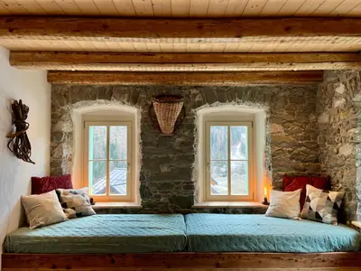 a bed in a room with two windows at Appartamenti La Rocia in Rocca Pietore
