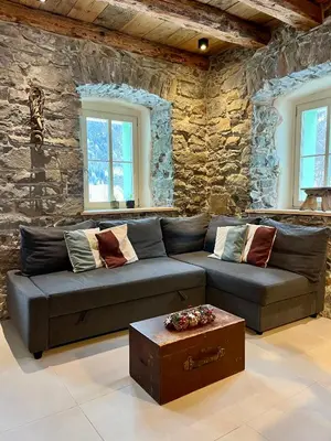 a living room with a couch and a stone wall at Appartamenti La Rocia in Rocca Pietore