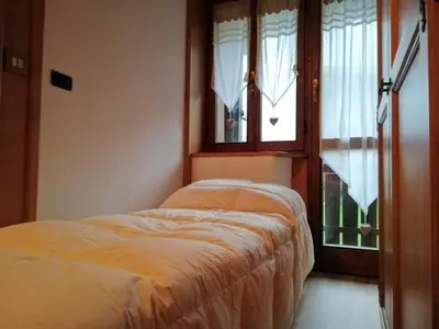 two beds in a room with a window at CASA VACANZE MIRAMONTI - appartamento con balcone con vista sulle Dolomiti in Borca di Cadore