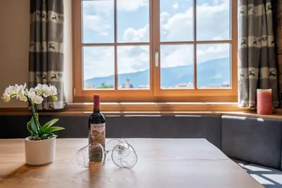 a bottle of wine and glasses on a table with a window at Rodererhof in Laion