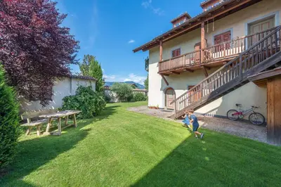 a woman walking her dog in the yard of a house at Glögglhof in Appiano sulla Strada del Vino