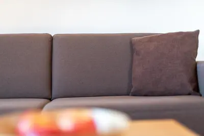 a couch with a brown pillow and a table at Glögglhof in Appiano sulla Strada del Vino