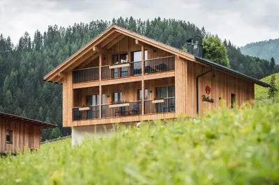 a large wooden building with a balcony at Batacör - Natures Heartbeat in San Vigilio Di Marebbe