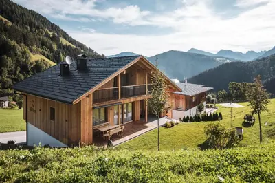 a house on a hill with mountains in the background at Batacör - Natures Heartbeat in San Vigilio Di Marebbe