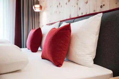 a row of red and white pillows on a bed at Batacör - Natures Heartbeat in San Vigilio Di Marebbe