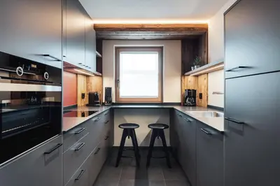 a large kitchen with two bar stools in the middle at Batacör - Natures Heartbeat in San Vigilio Di Marebbe