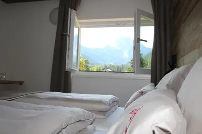 two beds in a room with a large window at Garni Bergblick in Braies