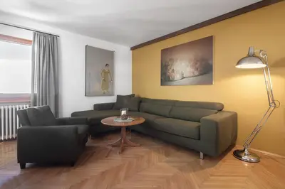 a living room with a green couch and a table at ARTEFUGIUM panoramico in Selva di Val Gardena