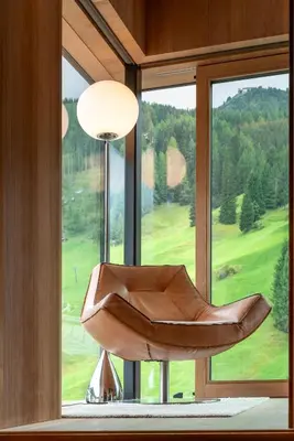 a leather chair sitting in front of a window at ARTEFUGIUM panoramico in Selva di Val Gardena