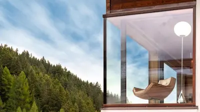 a window of a building with a view of a forest at ARTEFUGIUM panoramico in Selva di Val Gardena