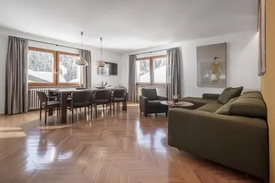 a living room with a couch and a table and chairs at ARTEFUGIUM panoramico in Selva di Val Gardena