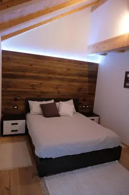 a bedroom with a bed with a wooden headboard at Alpine Home Fiemme in Predazzo