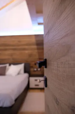 a door to a bedroom with a bed and a table at Alpine Home Fiemme in Predazzo