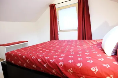 a bedroom with a red bed with a window at Alpine Home Fiemme in Predazzo