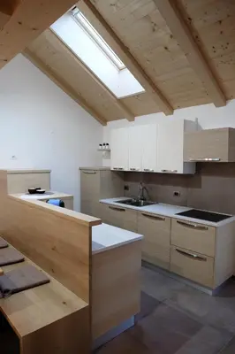 a large kitchen with white cabinets and a skylight at Alpine Home Fiemme in Predazzo