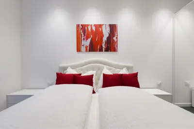 two white beds with red pillows in a bedroom at Apartment Hanni in Merano