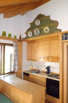 a kitchen with wooden cabinets and a stove top oven at Casa Venturini in Moena