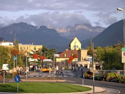 a city street with mountains in the background with a bus at Loft del Talvera 1 in Bolzano