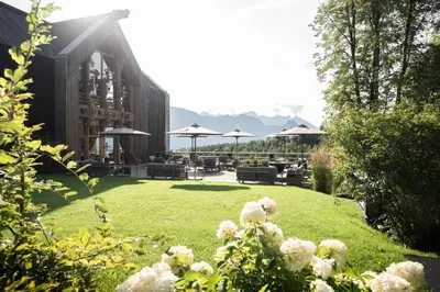 a garden with chairs and umbrellas on a lawn at ADLER Lodge RITTEN in Soprabolzano