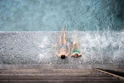 a man laying in the water in a swimming pool at ADLER Lodge RITTEN in Soprabolzano