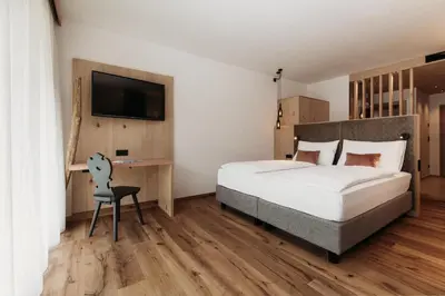 a bedroom with a bed and a desk and a tv at Weingut & Genusshotel Spitalerhof Superior in Chiusa