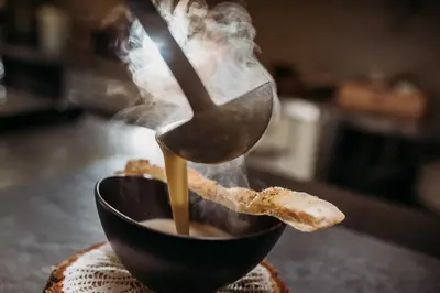 a cup of coffee with a spoon and a piece of bread at Weingut & Genusshotel Spitalerhof Superior in Chiusa