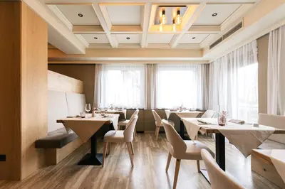 a restaurant with tables and chairs and windows at Weingut & Genusshotel Spitalerhof Superior in Chiusa