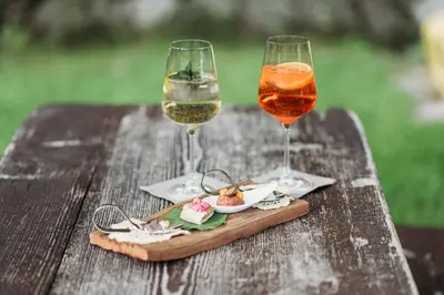 two glasses of wine and a plate of food on a wooden table at Weingut & Genusshotel Spitalerhof Superior in Chiusa