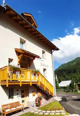 a building with a yellow balcony on the side of it at Apartments Fabiola in Arabba