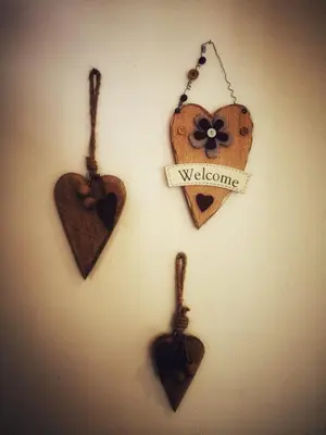 four wooden hearts hanging on a wall with a welcome sign at Apartments Fabiola in Arabba