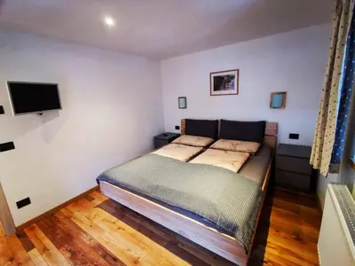 a small bedroom with a bed and a television at Apartments Fabiola in Arabba
