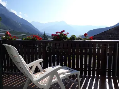 a white chair sitting on a deck with a view of mountains at GRETL - Residence in Parcines