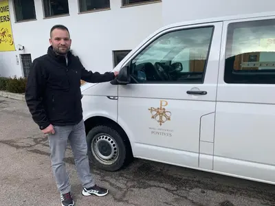 a man is standing next to a white van at Hotel Pontives in Ortisei