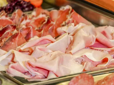 a bunch of ham and other meats in a display case at Hotel Pontives in Ortisei