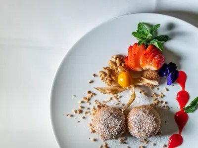 a white plate with a dessert with strawberries and nuts at Hotel Pontives in Ortisei