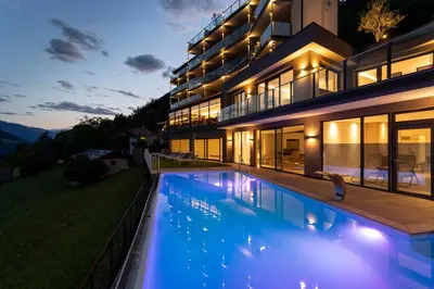 a house with a swimming pool at night at Hotel Lechner in Tirolo