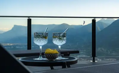 two wine glasses sitting on a table on a balcony at Hotel Lechner in Tirolo