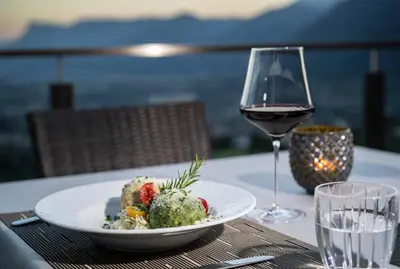 a plate of food and a glass of wine on a table at Hotel Lechner in Tirolo