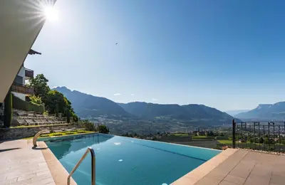 a swimming pool with mountains in the background at Hotel Lechner in Tirolo